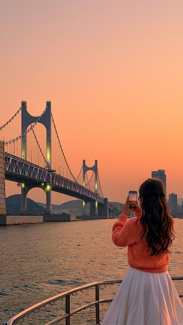 面向广安大桥拍日落照片的游客