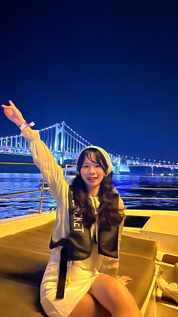 在夜景前的游船甲板上举手的游客