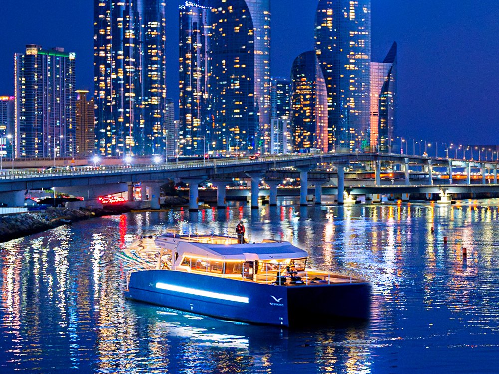 在 Marine City 夜景前驶过水营江的海云台河川游船