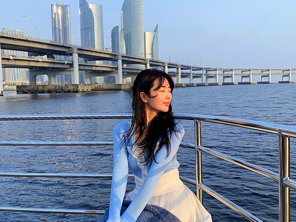 以广安大桥和 Marine City 为背景坐在游船栏杆上的游客